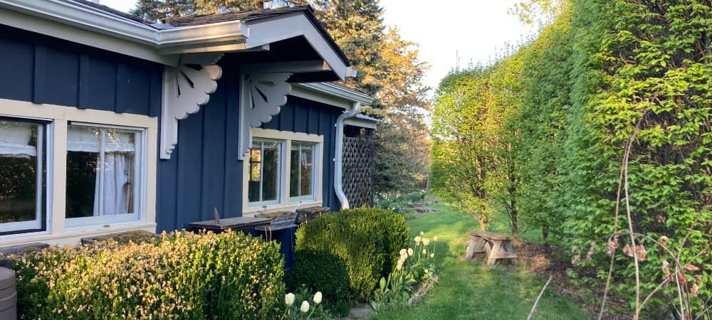 exterior view of grey and white trimmed garden shed with water barrel vine covered trellis