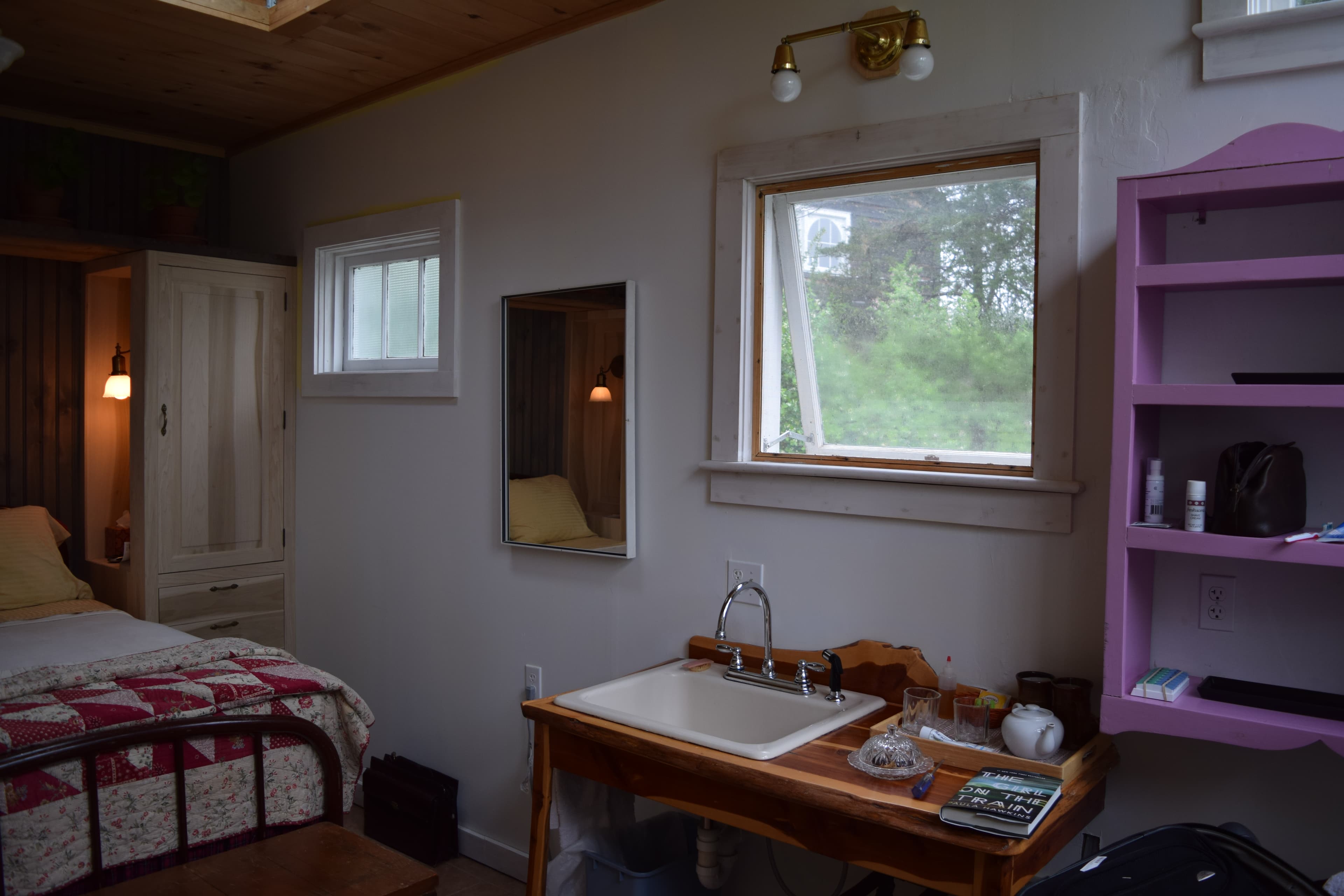 Roomy shower with smooth stone and tile walls in black with white trim. Shower head has water flowing from it.