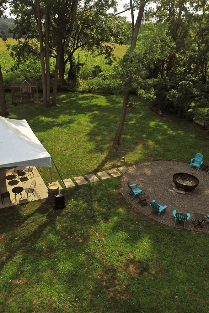 Aerial view of a green backyard with a fire pit, seating area, and a tent.